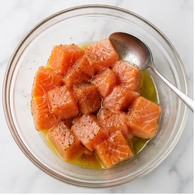 Step 1: Tossing salmon cubes with oil and seasoning