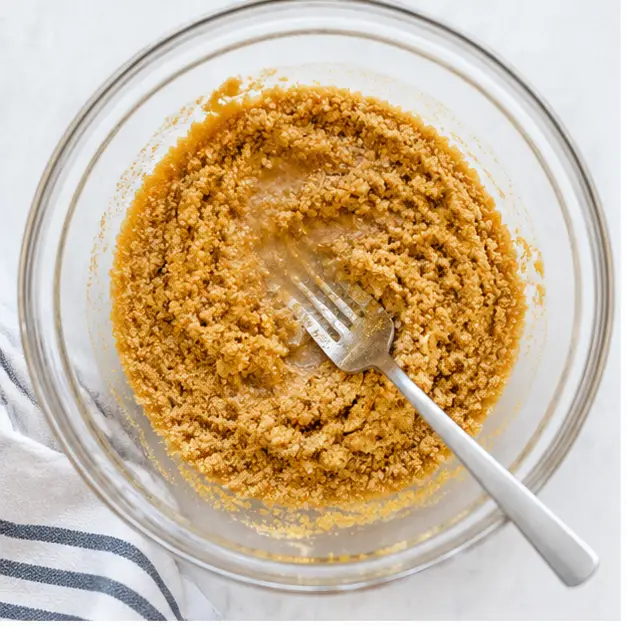 Step 1: Mixing graham cracker crumbs with melted butter