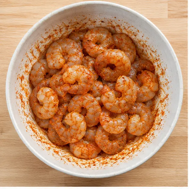 Step 1: Tossing raw shrimp with Cajun seasoning in a bowl