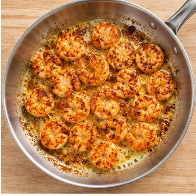Step 2: Searing seasoned shrimp in a hot buttered skillet until golden