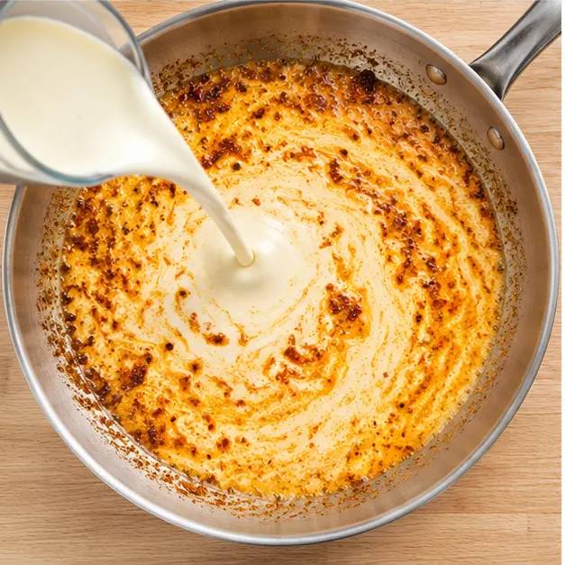 Step 3: Pouring heavy cream into the skillet to build the sauce