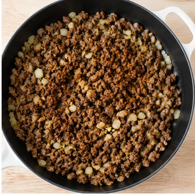 Adding onion garlic and taco seasoning to browned beef