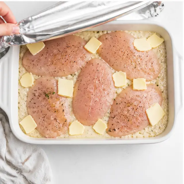 Step 3: Arrange chicken fillets over the rice, scatter butter, cover with foil