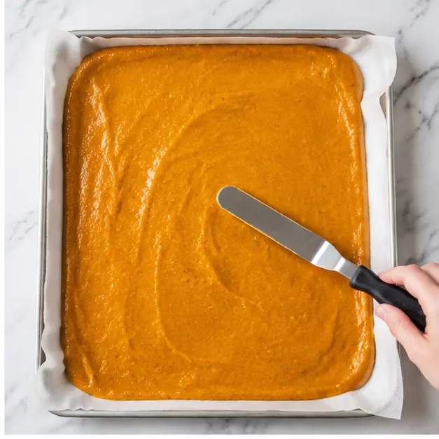 Spread the orange batter evenly in the parchment lined jelly roll pan