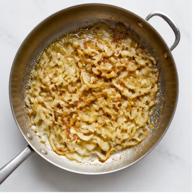 Step 1: Caramelizing sliced yellow onions in melted butter until golden brown