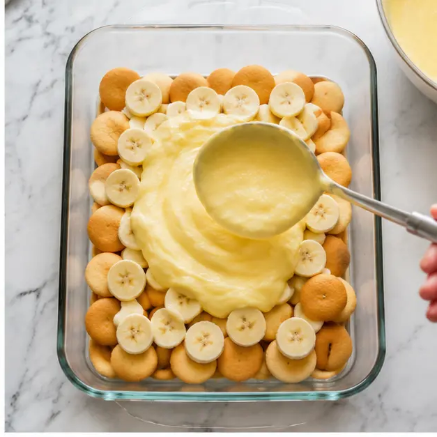 Arranging vanilla wafer cookies, sliced ripe bananas, and warm custard in even layers
